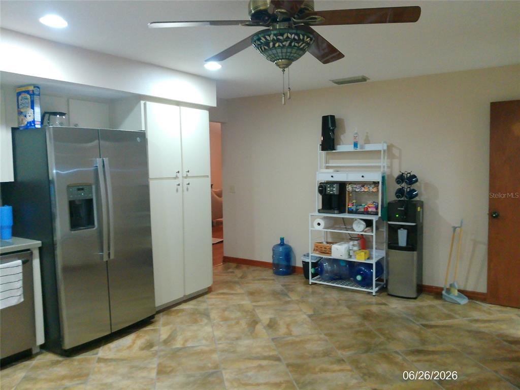 A kitchen with tile flooring, a stainless steel refrigerator, and a white metal shelving unit — 1601 ARCHERS PATH, LAKELAND, FL