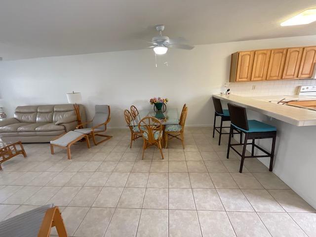 An open-concept living and dining area features tile flooring, a ceiling fan, and wooden cabinetry — 1600 NE Dixie Highway # 107, Jensen Beach FL 34957, JENSEN BEACH, FL
