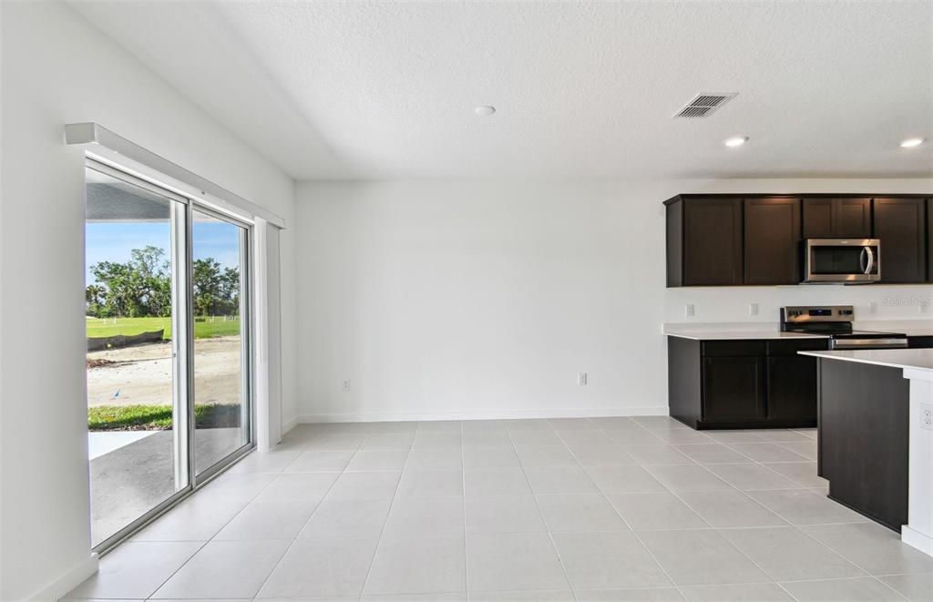 A bright dining area with light tile floors, white walls, and a sliding glass door — 10818 SAPPHIRE BREEZE COVE, PARRISH, FL
