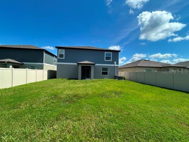 The backyard of a two-story house features a lawn enclosed by a white vinyl fence — 22164 N CALISTO WAY N, LAND O LAKES, FL