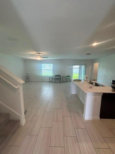 An open-concept living area features light-colored tile flooring, a kitchen island, and a staircase — 22164 N CALISTO WAY N, LAND O LAKES, FL
