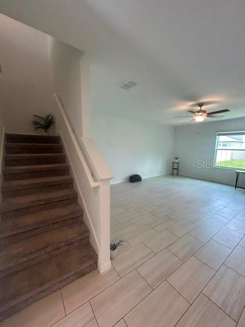 A carpeted staircase leads to an upper level next to an open-concept tiled living area — 22164 N CALISTO WAY N, LAND O LAKES, FL