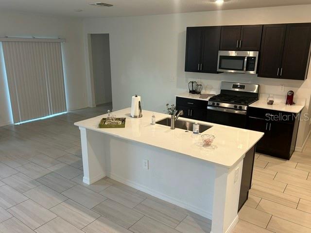 A modern kitchen features dark cabinets, a white quartz island, and light-colored tile flooring — 22164 N CALISTO WAY N, LAND O LAKES, FL