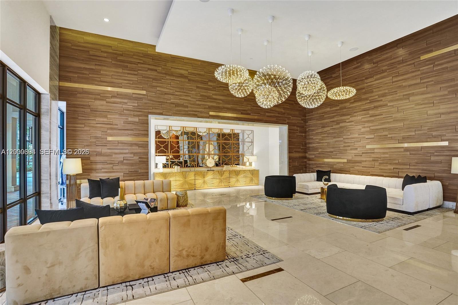 A modern lobby features wood-paneled walls, large spherical pendant lights, and plush seating areas — 101 E Camino Real # 517, Boca Raton FL 33432, BOCA RATON, FL