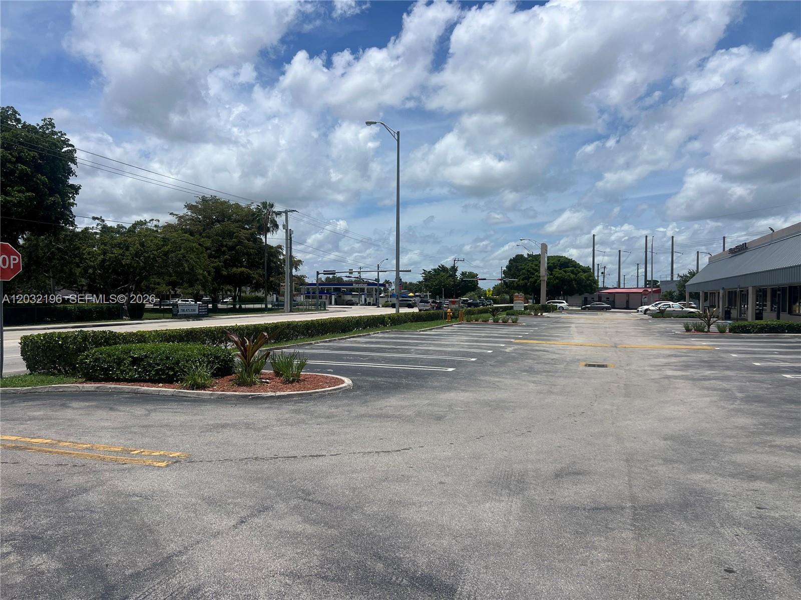 An outdoor parking lot features marked spaces, a landscaped island, and a nearby commercial building — SW 107th Ave, Miami FL 33173, MIAMI, FL