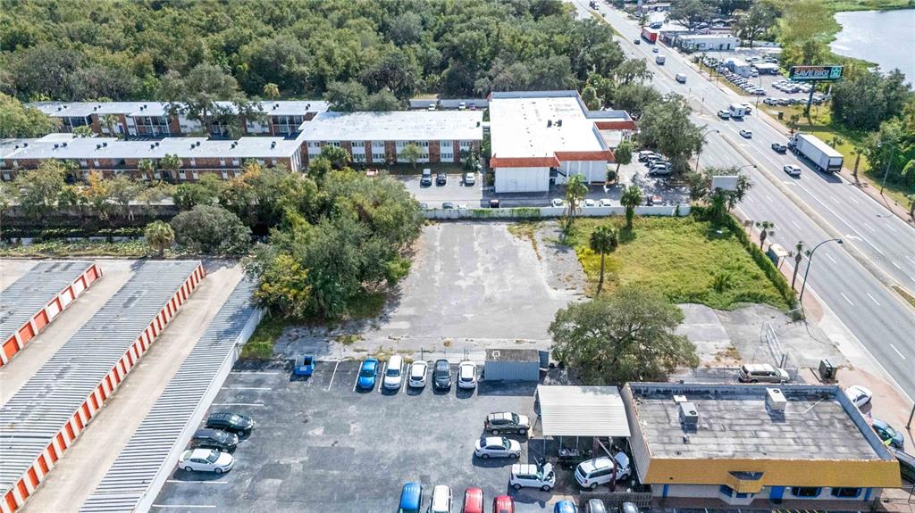 An aerial view shows a vacant paved lot adjacent to commercial buildings and a highway — 4849 S ORANGE BLOSSOM TRAIL, ORLANDO, FL