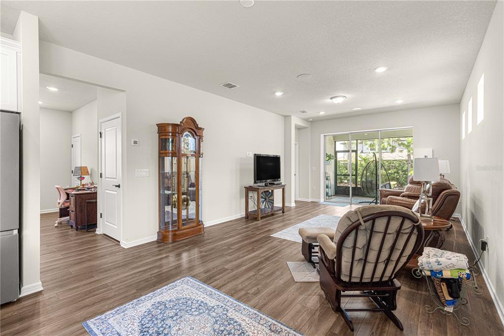 A living room features wood-look flooring, a grandfather clock, and a sliding door to a patio — 5942 SW 93 CIRCLE, OCALA, FL