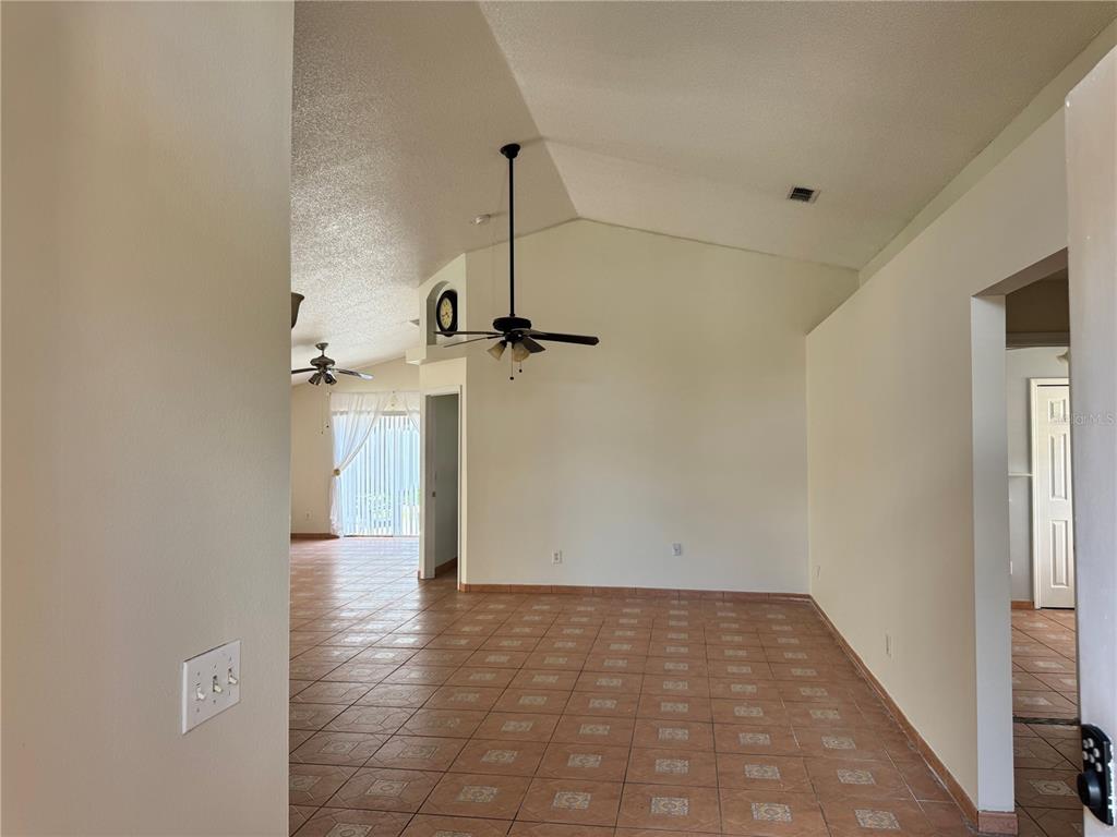 A living area with vaulted ceilings, a ceiling fan, and brown tile flooring — 260 PICCOLO WAY, DAVENPORT, FL