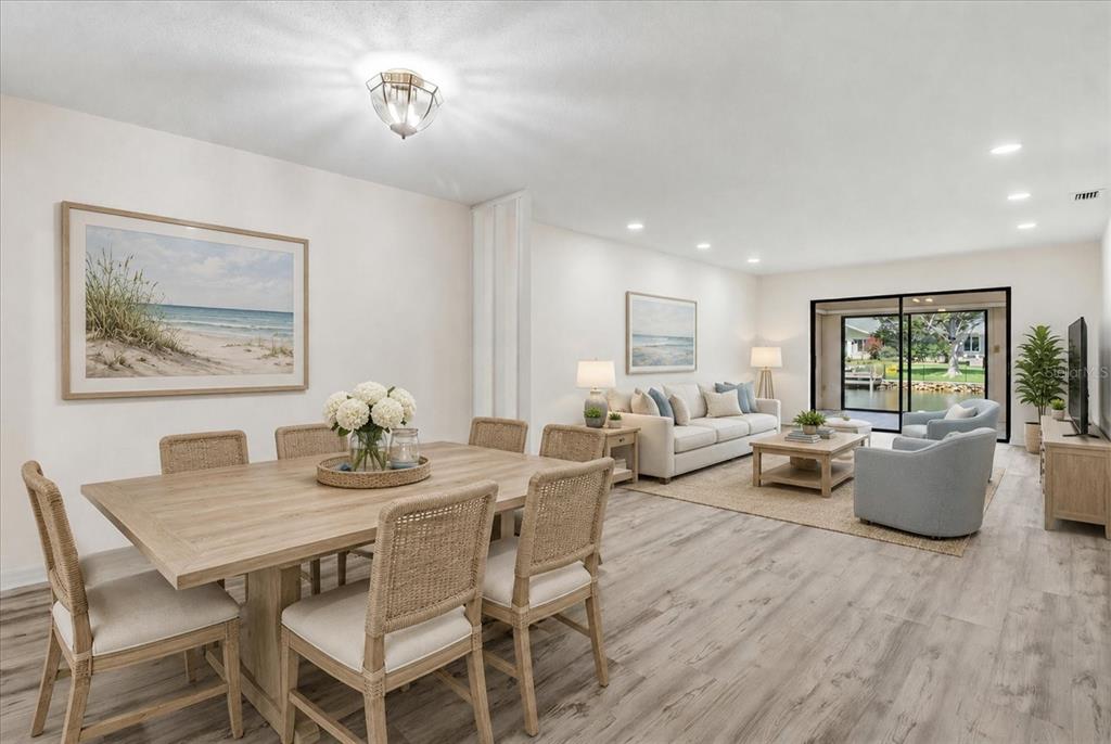 An open-concept living and dining area features light wood flooring, coastal decor, and sliding glass doors — 11621 W RIVERHAVEN DRIVE, HOMOSASSA, FL
