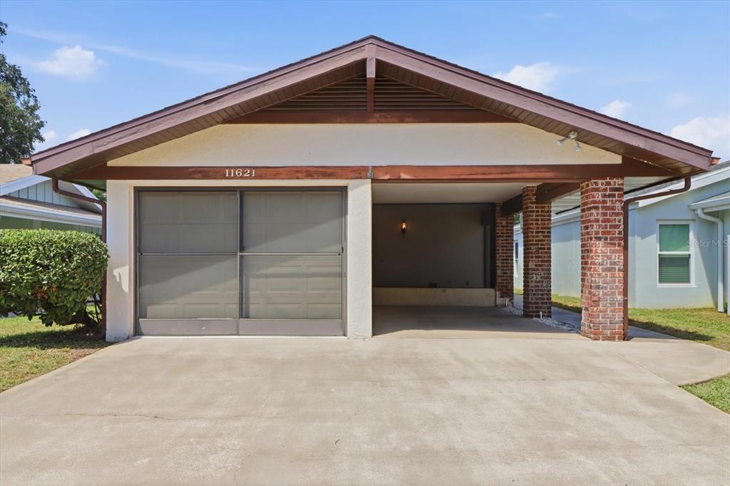 The exterior of a house features a single-car garage and an adjacent open carport — 11621 W RIVERHAVEN DRIVE, HOMOSASSA, FL