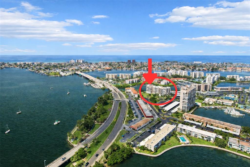 A screened-in balcony with a table, two chairs, and a view of a waterfront marina — 7400 SUN ISLAND DRIVE S UNIT 802, SOUTH PASADENA, FL