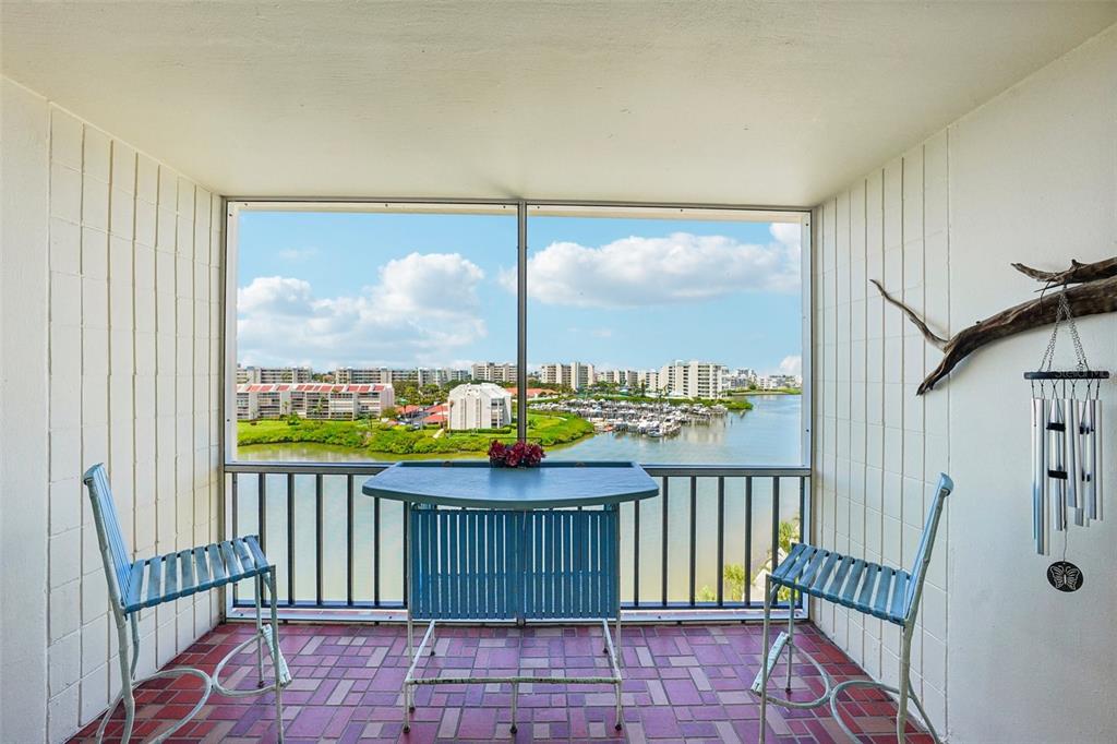 A screened balcony features a tiled floor, outdoor furniture, and a view of a marina — 7400 SUN ISLAND DRIVE S UNIT 802, SOUTH PASADENA, FL