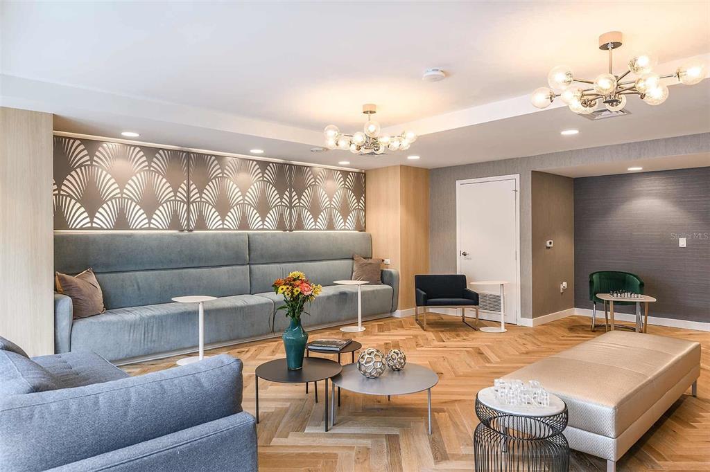A modern lounge area features a long blue sofa, herringbone wood floors, and two chandeliers — 415-3 E PINE STREET, ORLANDO, FL