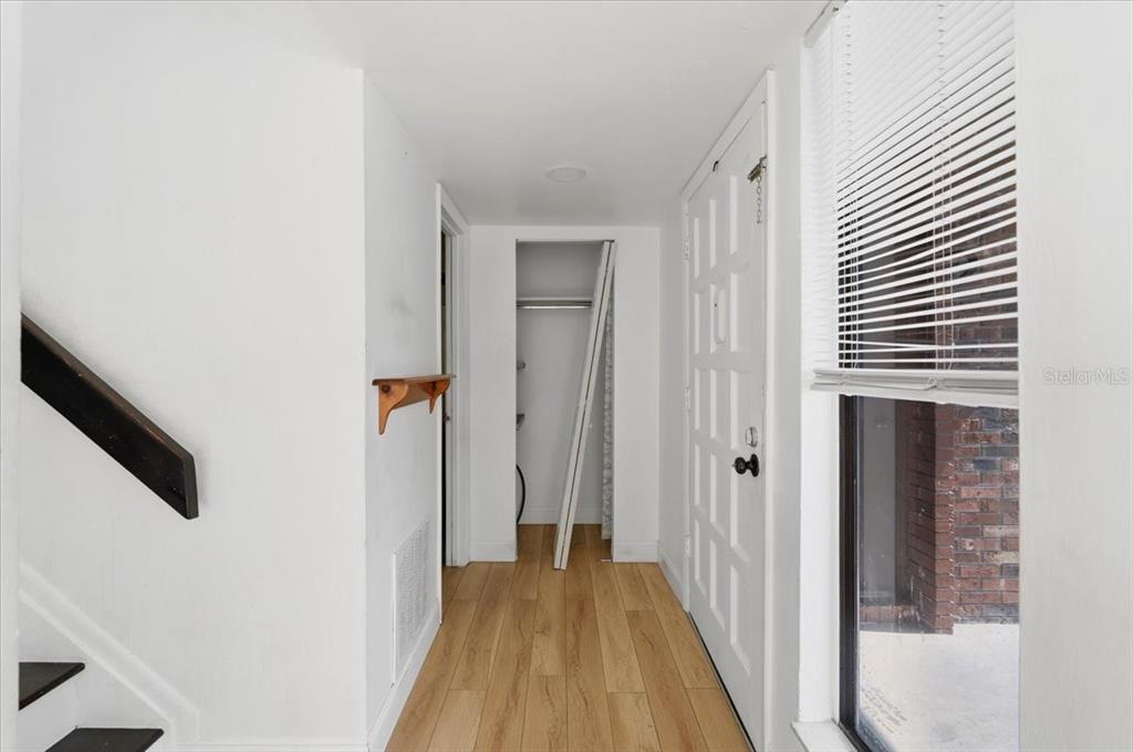 A hallway with light wood flooring, a white door, a closet, and a staircase railing — 1836 N CRYSTAL LAKE DRIVE UNIT 70, LAKELAND, FL