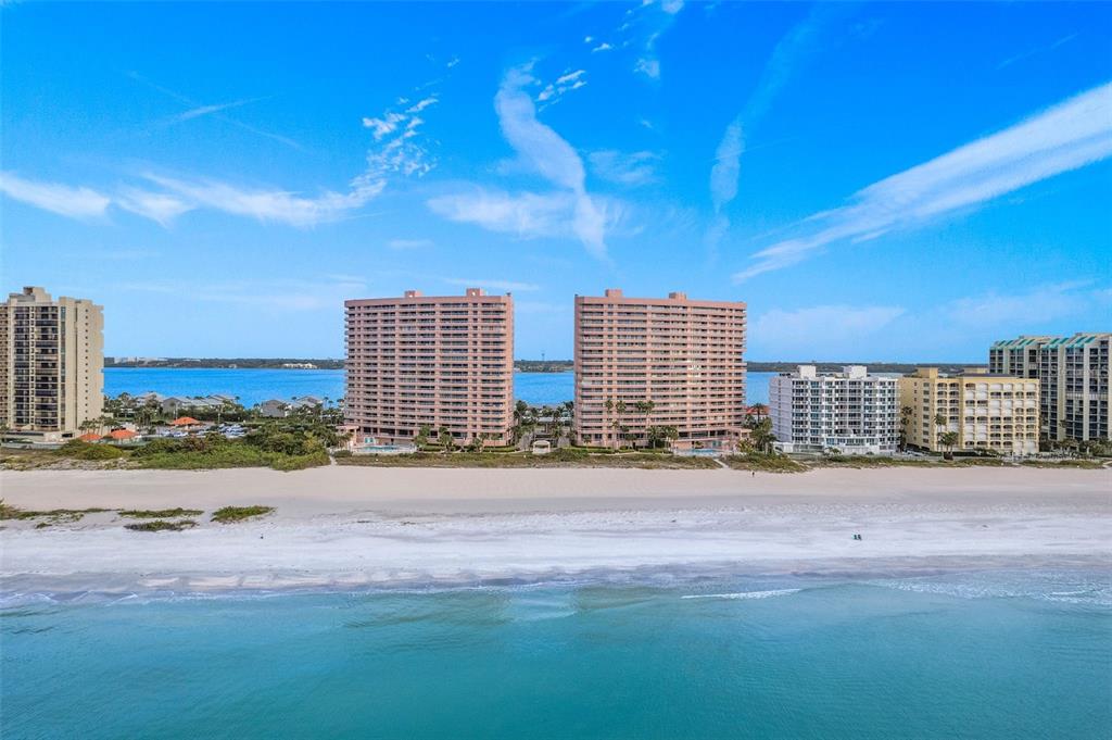 An aerial view of two tall, peach-colored beachfront condominiums surrounded by other coastal buildings — 1310 GULF BOULEVARD UNIT 4-G, CLEARWATER, FL