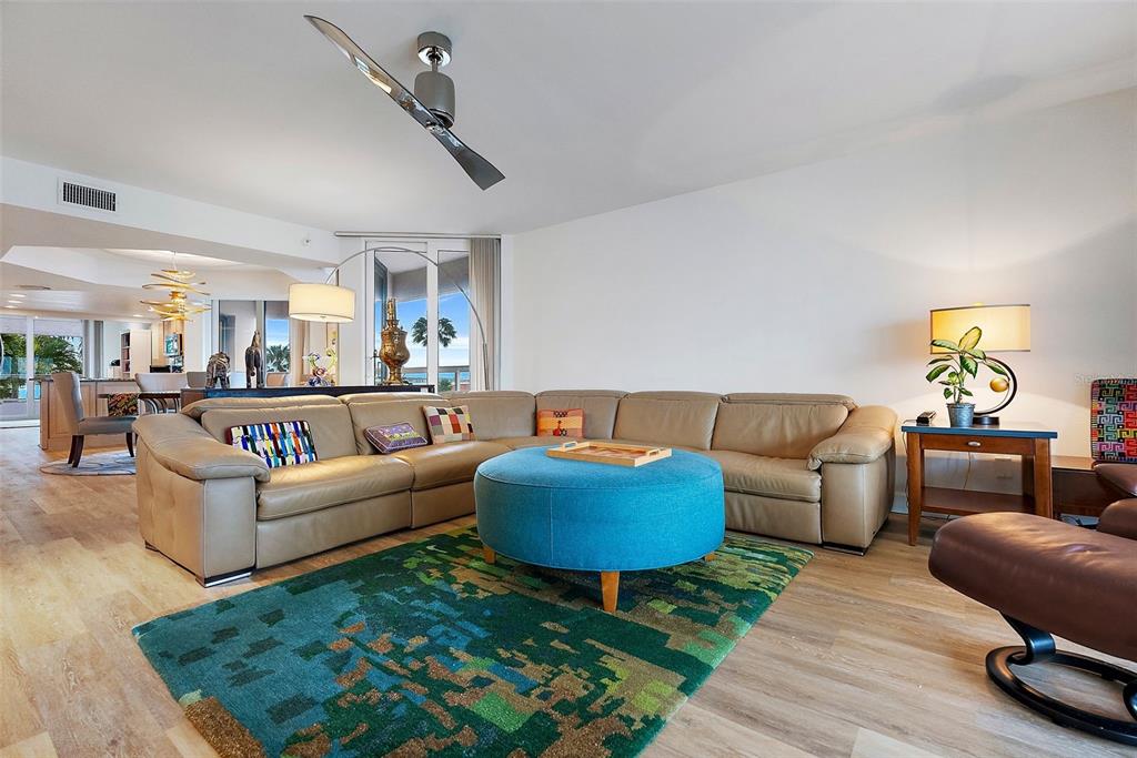 A living room features a tan sectional sofa, a blue ottoman, and a patterned rug — 1310 GULF BOULEVARD UNIT 4-G, CLEARWATER, FL