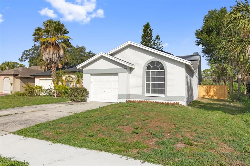 A single-story house with a white garage, arched window, and a grassy front yard — 11651 SUNSHINE POND ROAD, TAMPA, FL