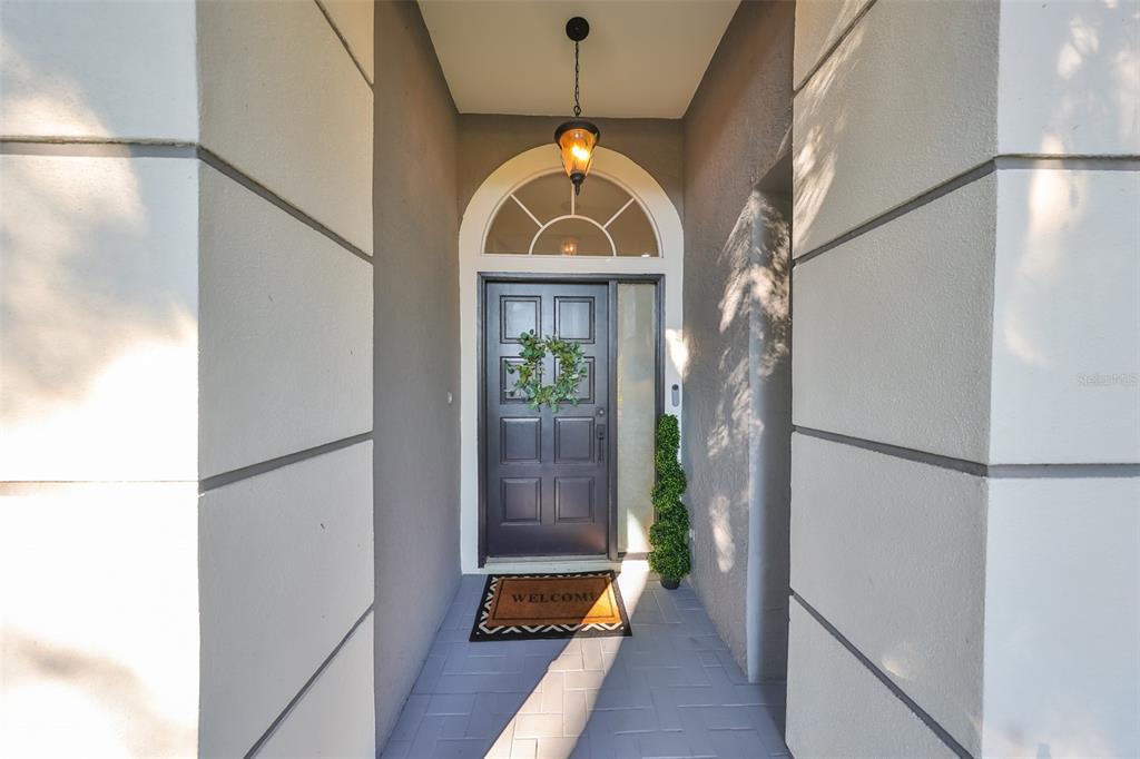 A front entryway features a dark gray door with a wreath under a hanging lantern — 9309 HAMPSHIRE PARK DRIVE, TAMPA, FL