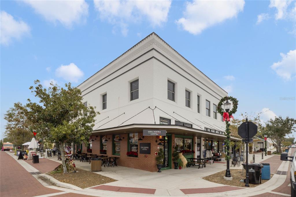 A two-story white building with a brick-faced corner storefront and outdoor seating area — 792 W MONTROSE STREET UNIT 205, CLERMONT, FL