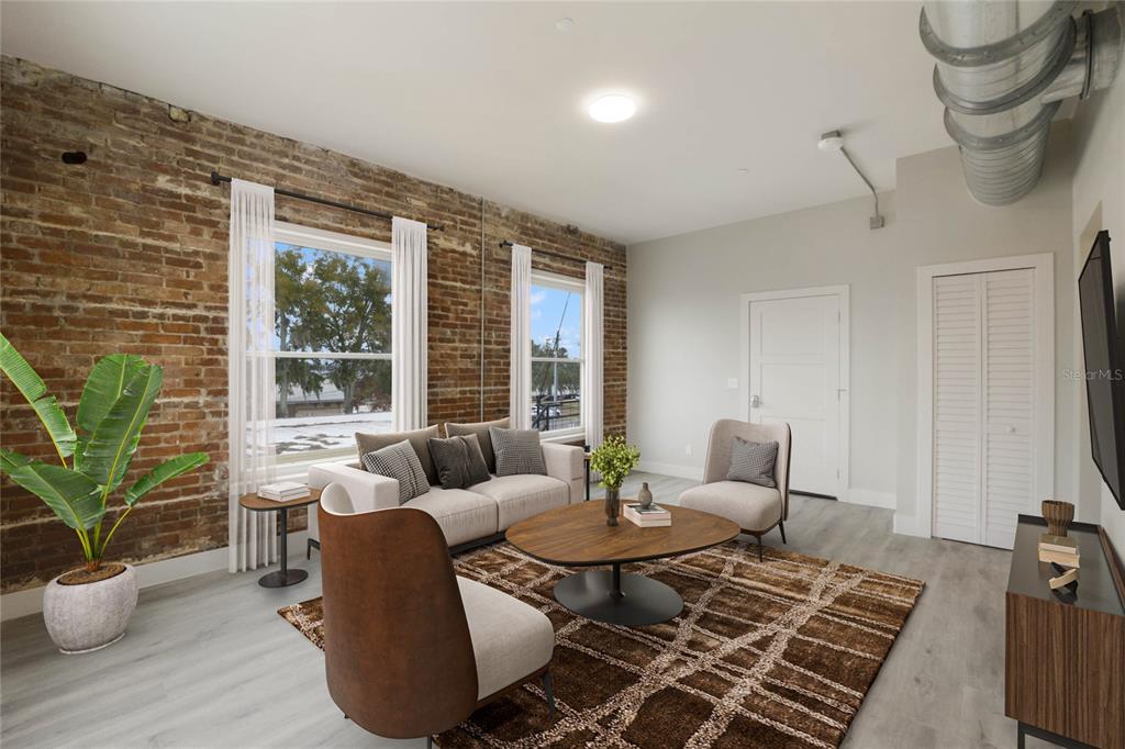 A living room features exposed brick walls, large windows, light wood flooring, and industrial ductwork — 792 W MONTROSE STREET UNIT 205, CLERMONT, FL
