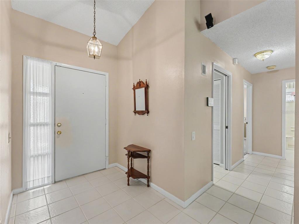 A bright entryway features a white front door, tiled floors, and a vaulted ceiling — 3341 PLAYER DRIVE, NEW PORT RICHEY, FL