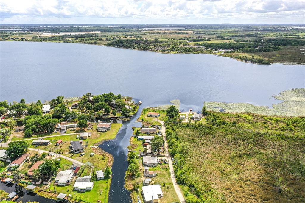 An aerial view shows a narrow canal leading into a large lake near residential homes — 3386 MAPLE LANE, HAINES CITY, FL