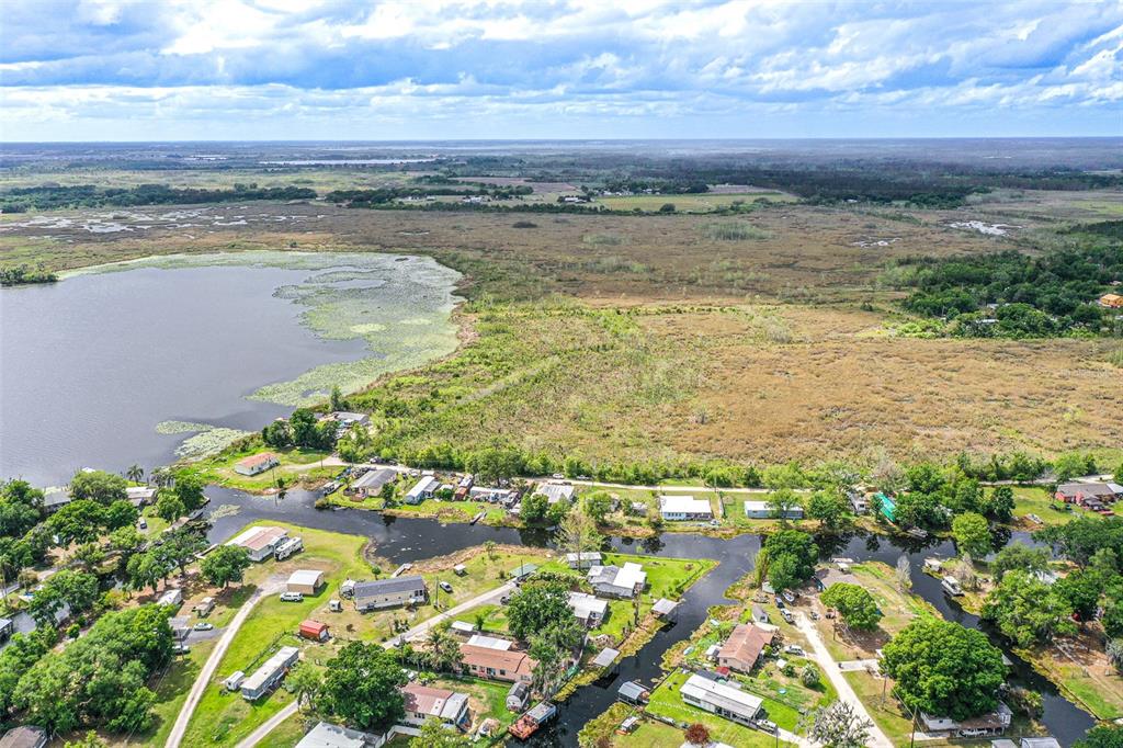An aerial view shows a residential area with houses situated along a canal and lake — 3386 MAPLE LANE, HAINES CITY, FL