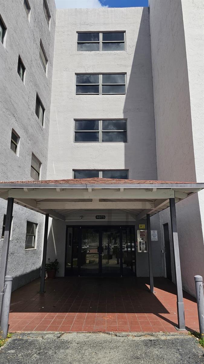 A covered entryway leads to the glass-paned front doors of a multi-story apartment building — 8075 NW 7th St # 401, Miami FL 33126, MIAMI, FL