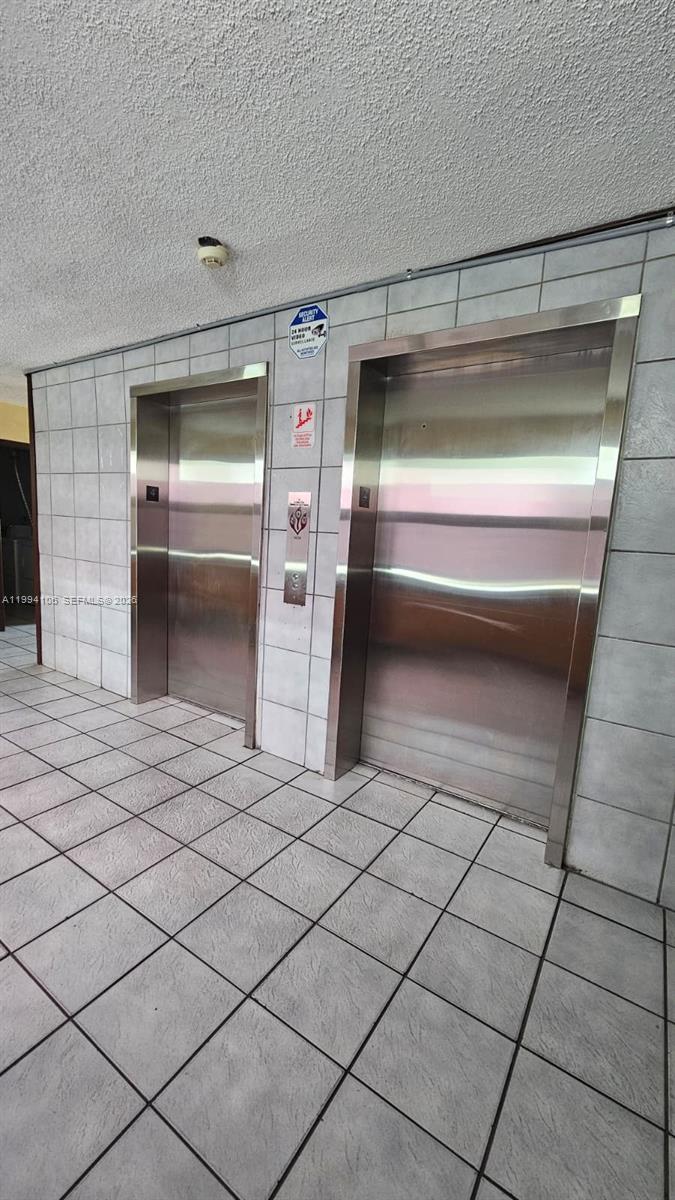 Two stainless steel elevator doors are set into a wall with white square tiles — 8075 NW 7th St # 401, Miami FL 33126, MIAMI, FL