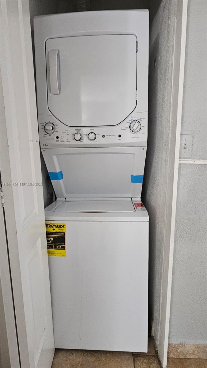 A white stacked washer and dryer unit is installed in a small closet — 8075 NW 7th St # 401, Miami FL 33126, MIAMI, FL