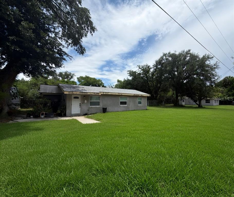 A single-story gray house with a white front door sits on a large grassy lot — 3316 W 5TH STREET, SANFORD, FL