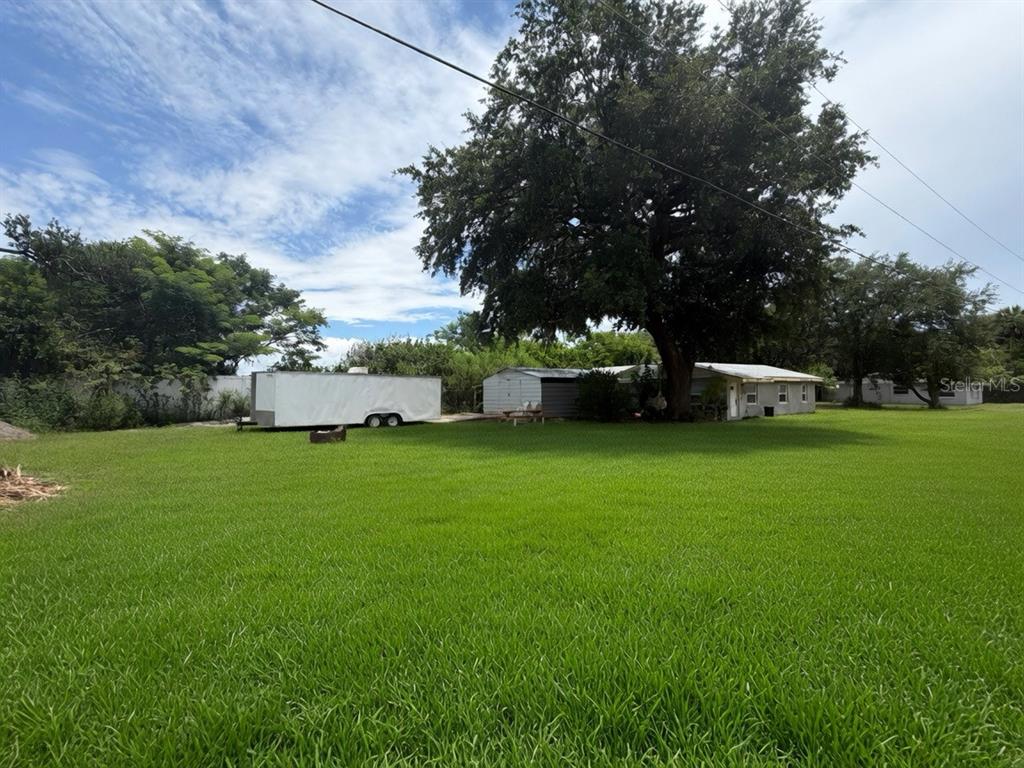 A large grassy yard features a white trailer and a small house under a tree — 3316 W 5TH STREET, SANFORD, FL