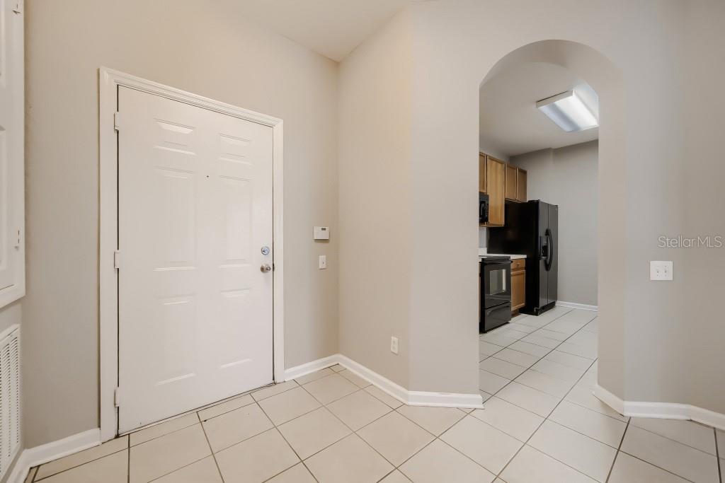 An entryway with tile flooring leads to a kitchen through an arched doorway — 2484 SAN TECLA STREET UNIT 204, ORLANDO, FL