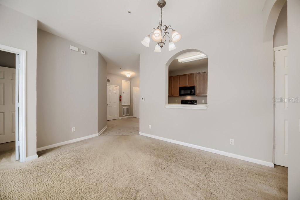 A carpeted dining area features a chandelier and an arched pass-through to the kitchen — 2484 SAN TECLA STREET UNIT 204, ORLANDO, FL