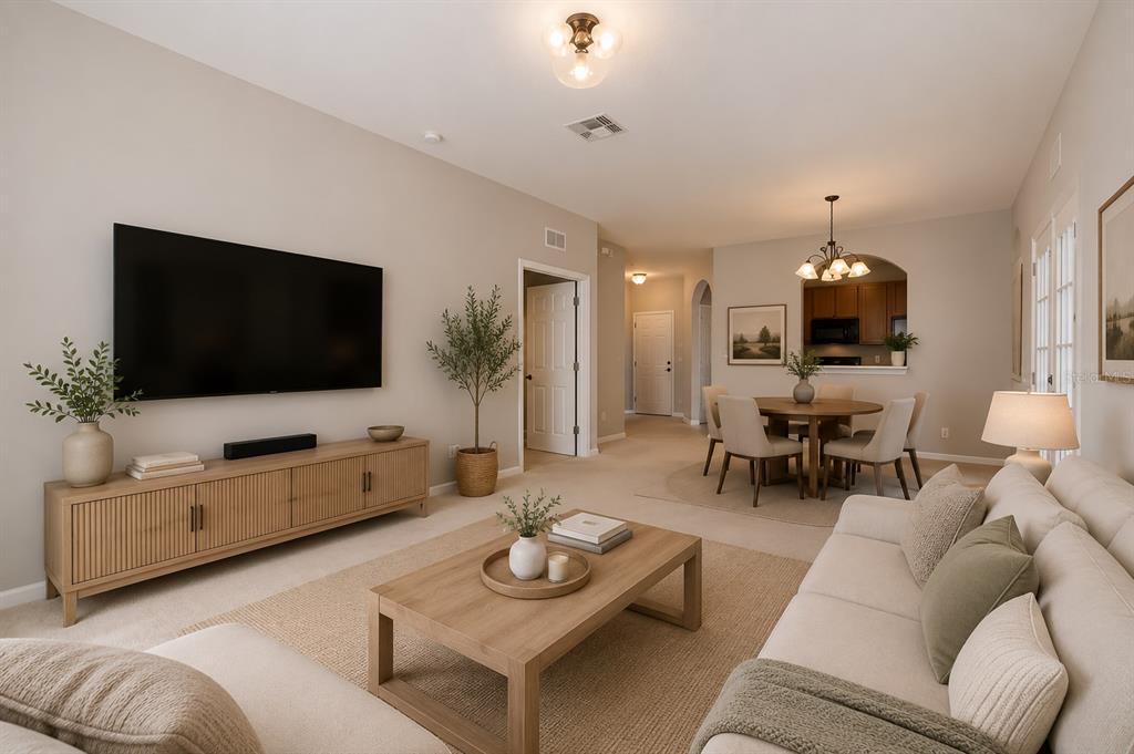 A living room with a television, wooden media console, coffee table, and adjacent dining area — 2484 SAN TECLA STREET UNIT 204, ORLANDO, FL