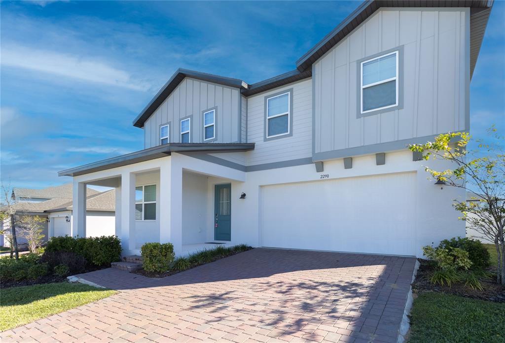 A two-story house with a white stucco facade, gray siding, and a paved driveway — 2290 RAVEN RIDGE ROAD, CLERMONT, FL