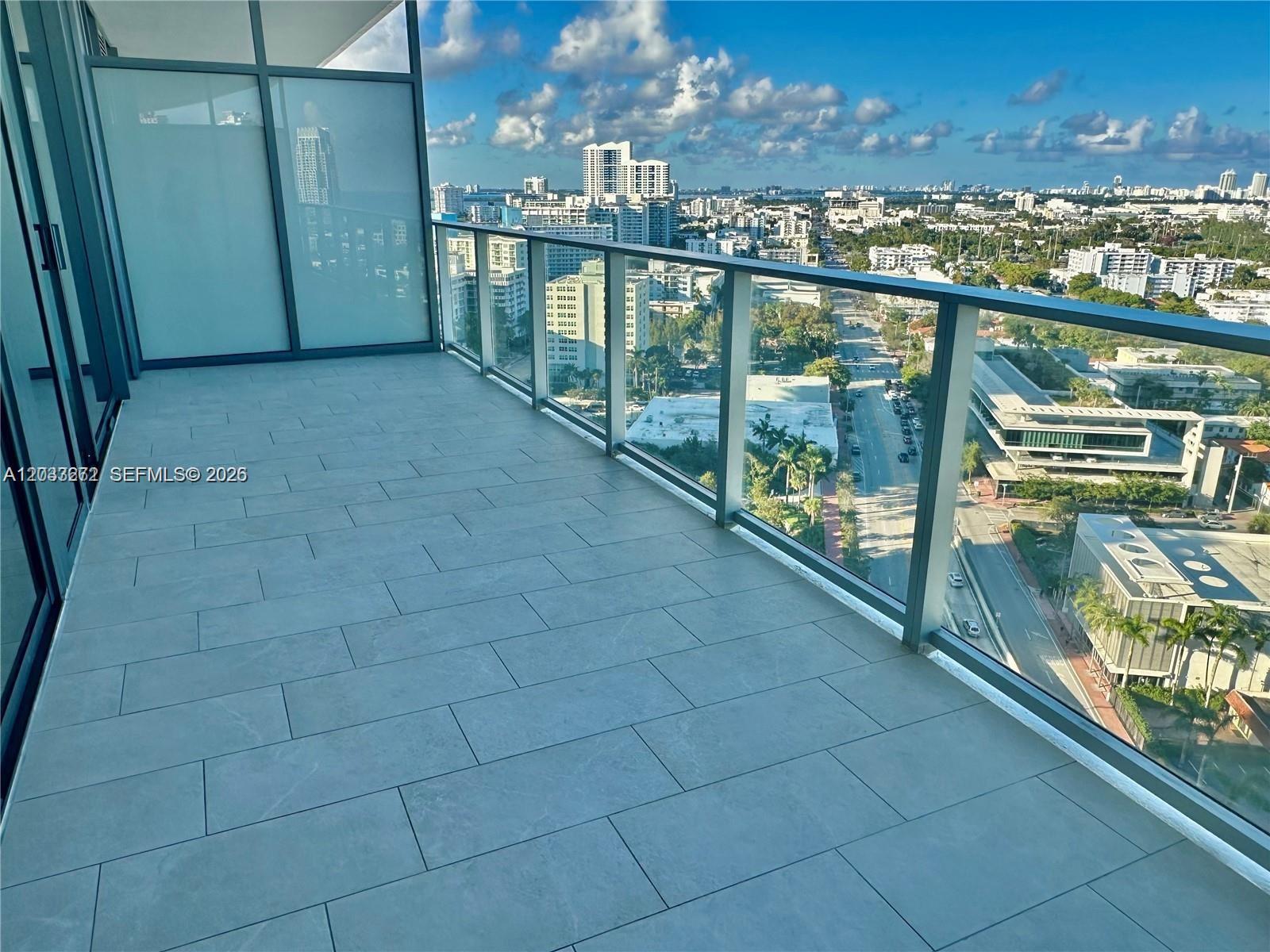 A high-rise balcony features gray tile flooring and a glass railing overlooking a city street — 500 Alton Rd # 2108, Miami Beach FL 33139, MIAMI BEACH, FL