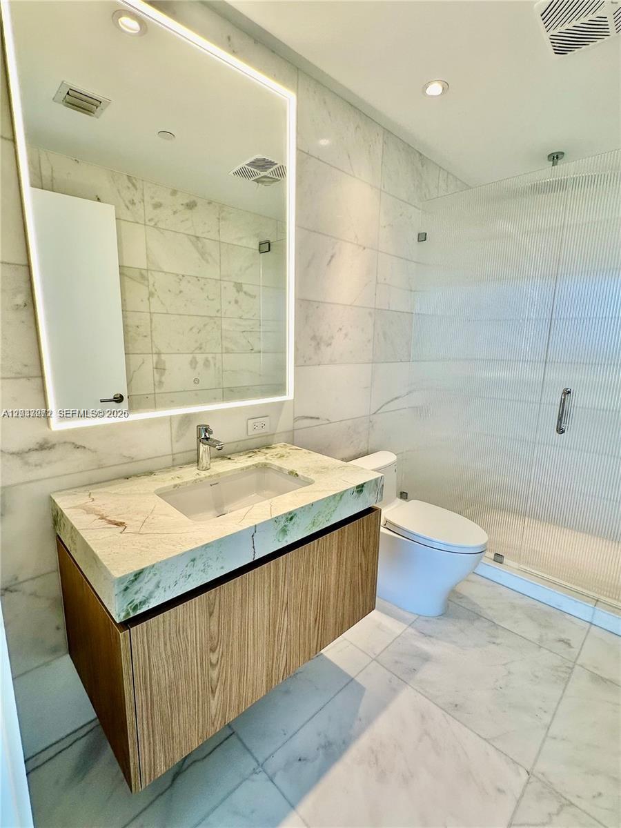 A modern bathroom features a floating wood vanity, marble countertop, and a glass-enclosed shower — 500 Alton Rd # 2108, Miami Beach FL 33139, MIAMI BEACH, FL
