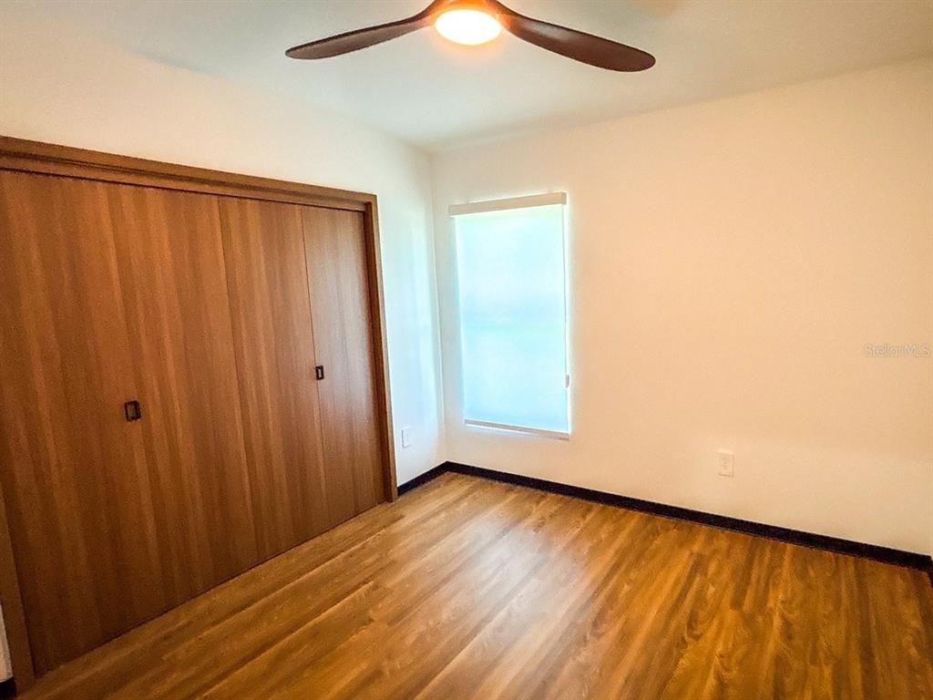 A bedroom features wood-look flooring, a large closet with sliding doors, and a ceiling fan — 4300 THUNDERBIRD ROAD, SEBRING, FL