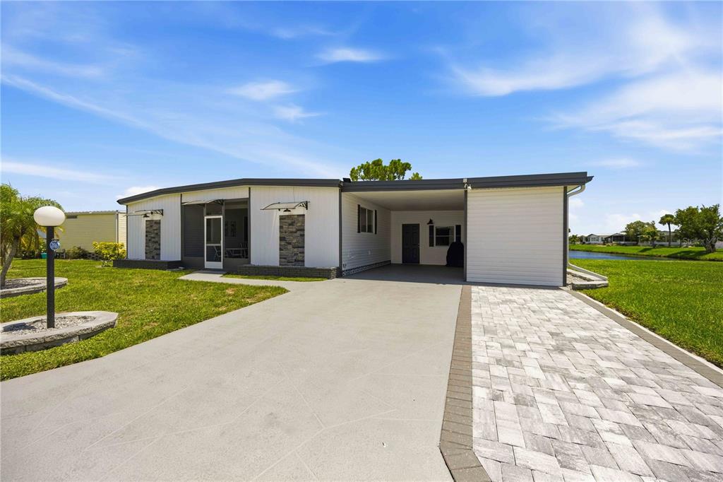 A single-story mobile home features a paved driveway, a carport, and a screened-in front porch — 206 TORTOLA WAY, NORTH PORT, FL