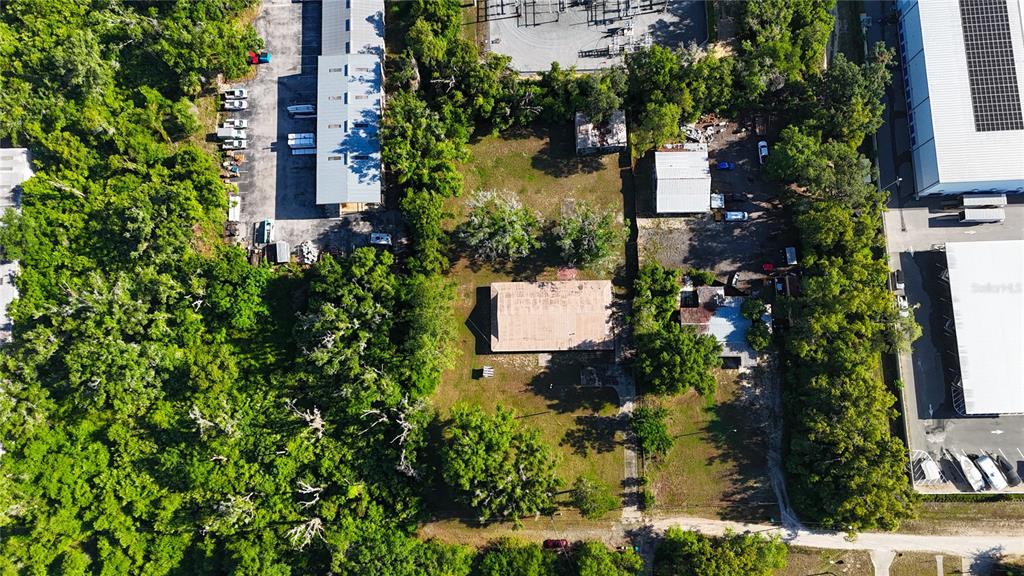 An aerial view shows a rectangular building on a lot surrounded by trees and warehouses — 13203 BLISSFIELD, ODESSA, FL