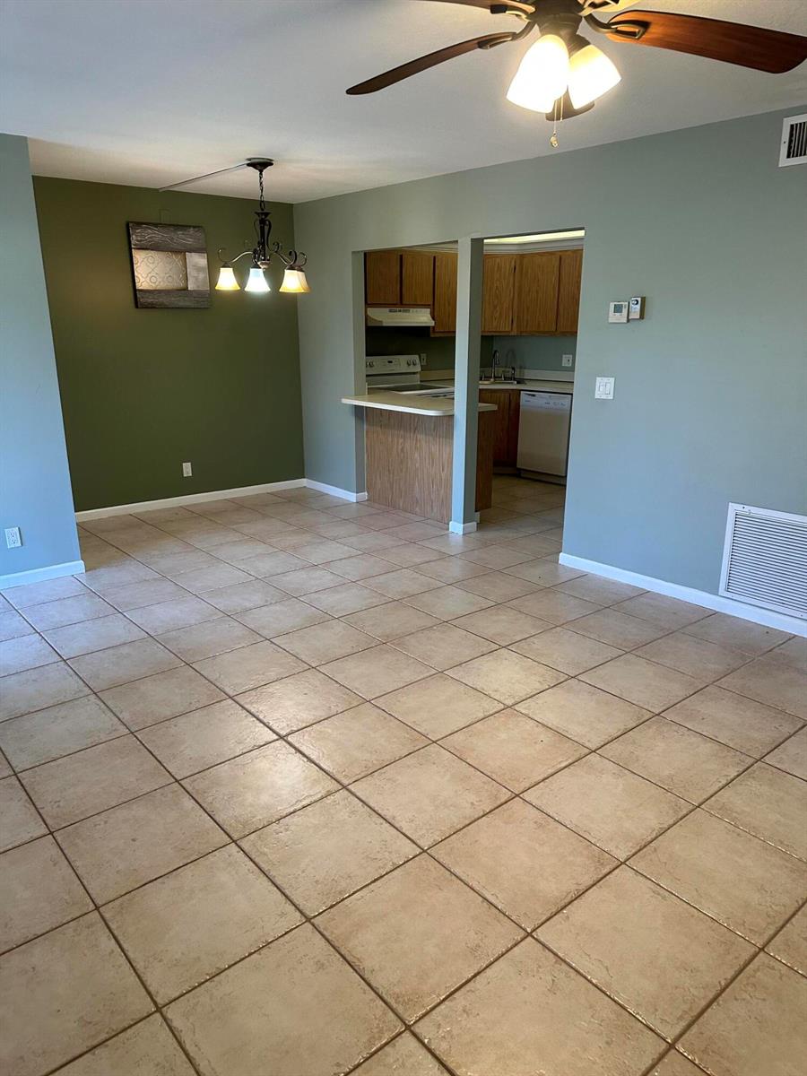An open-concept dining area with tile floors leads into a kitchen with wood cabinets — 436 Pine Glen Lane # 1, FL 33463, FL