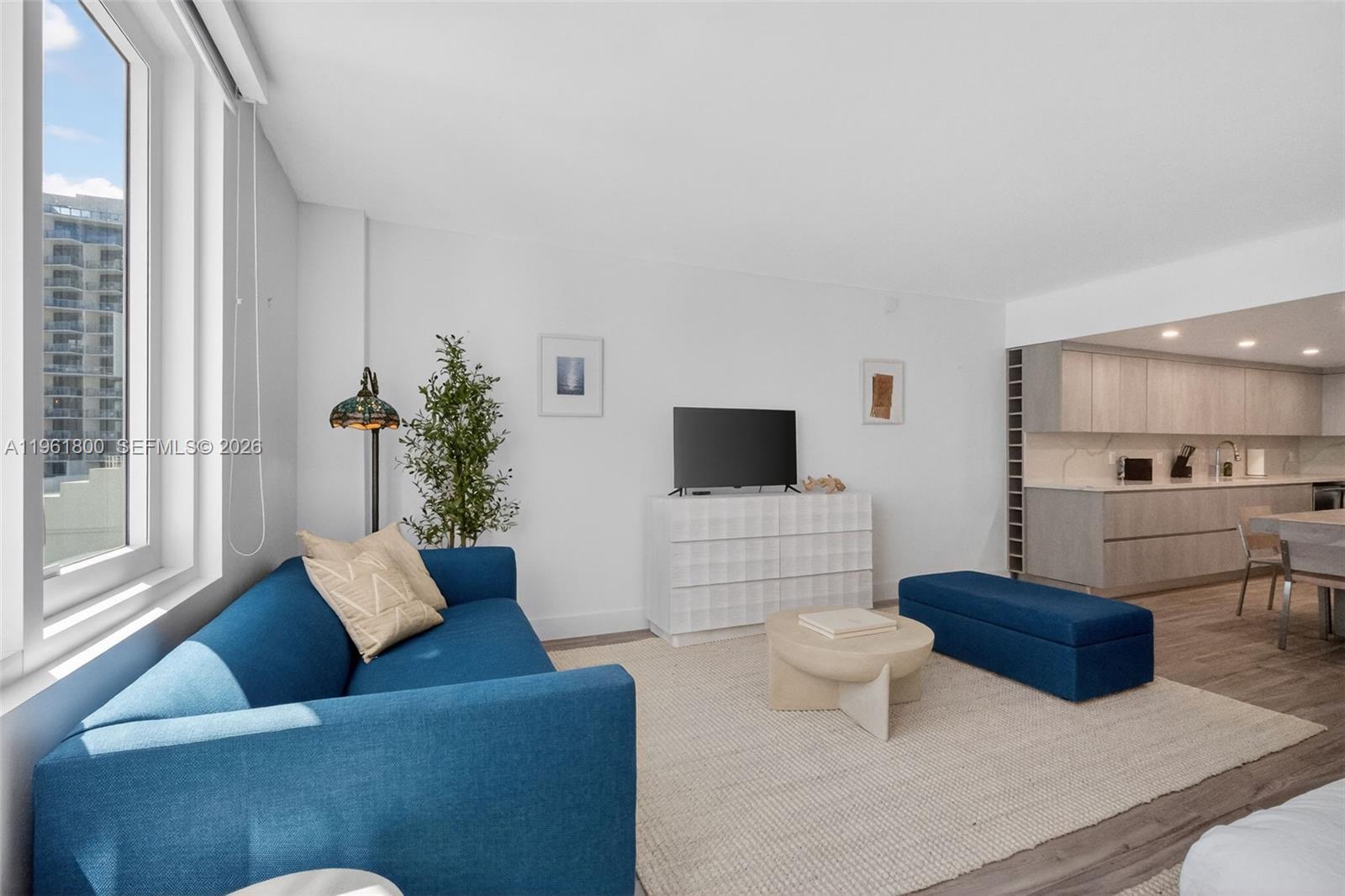 A living room features a blue sofa, a white dresser, and an open-concept kitchen — 2301 Collins Ave # 943, Miami Beach FL 33139, MIAMI BEACH, FL