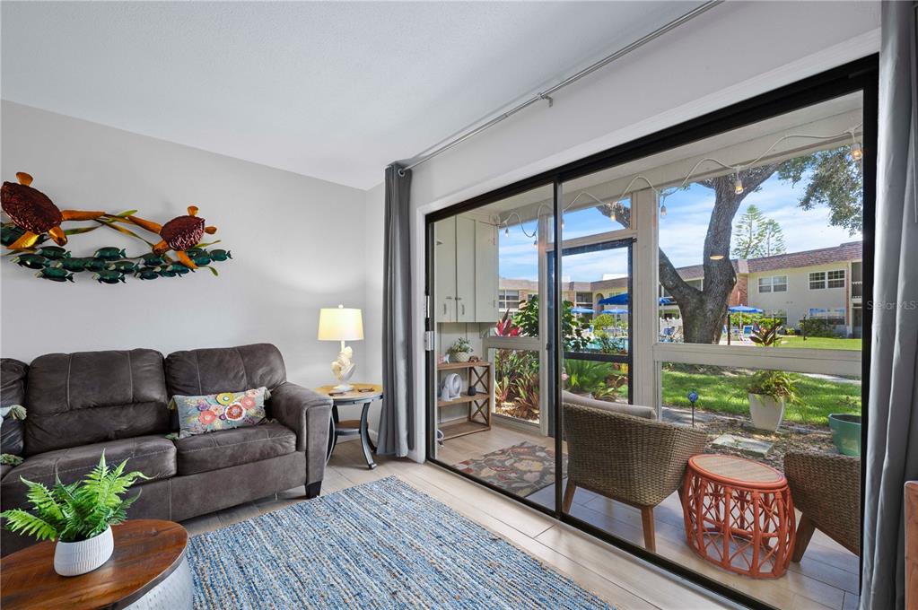 A living room with a brown sofa, blue rug, and sliding glass doors to a patio — 3800 SAXON DRIVE UNIT 19B, NEW SMYRNA BEACH, FL