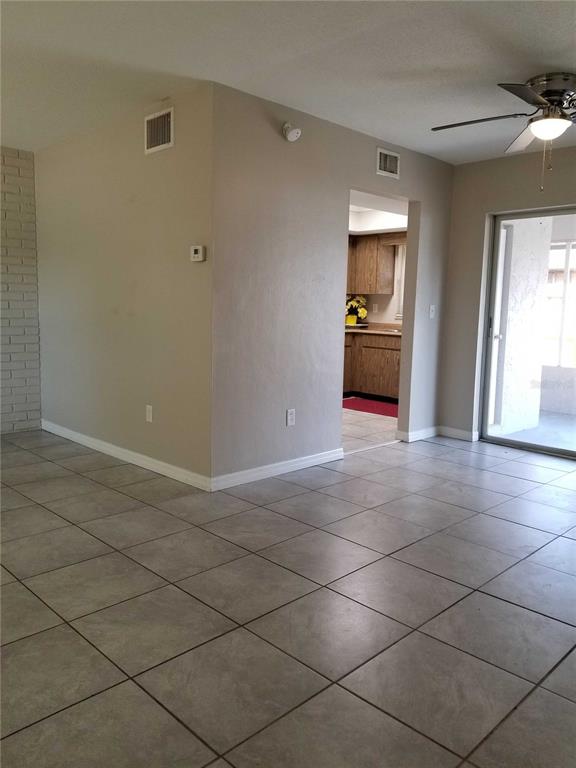 A room with light-colored tile flooring, a ceiling fan, and a doorway leading to a kitchen — 3366 CAMELOT DRIVE UNIT A & B, LARGO, FL