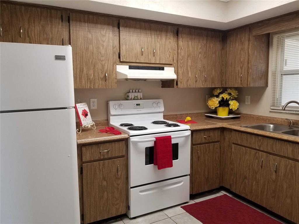 A kitchen features wood-grain cabinets, white appliances, and a tan laminate countertop — 3366 CAMELOT DRIVE UNIT A & B, LARGO, FL