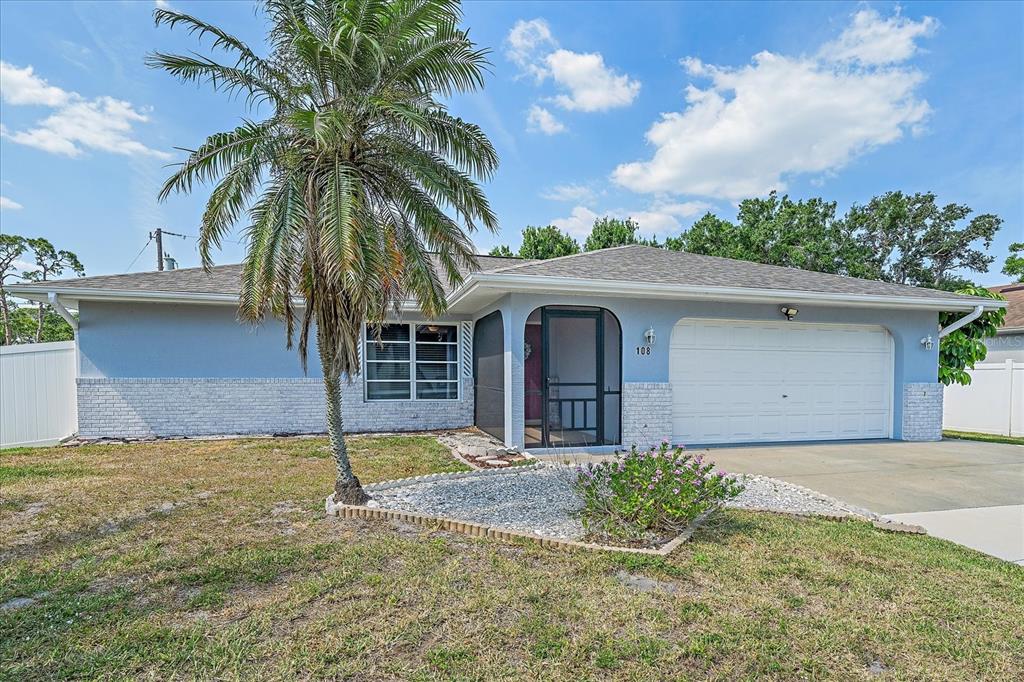 A single-story house with a blue exterior, white brick accents, a palm tree, and garage — 108 STANFORD ROAD, VENICE, FL