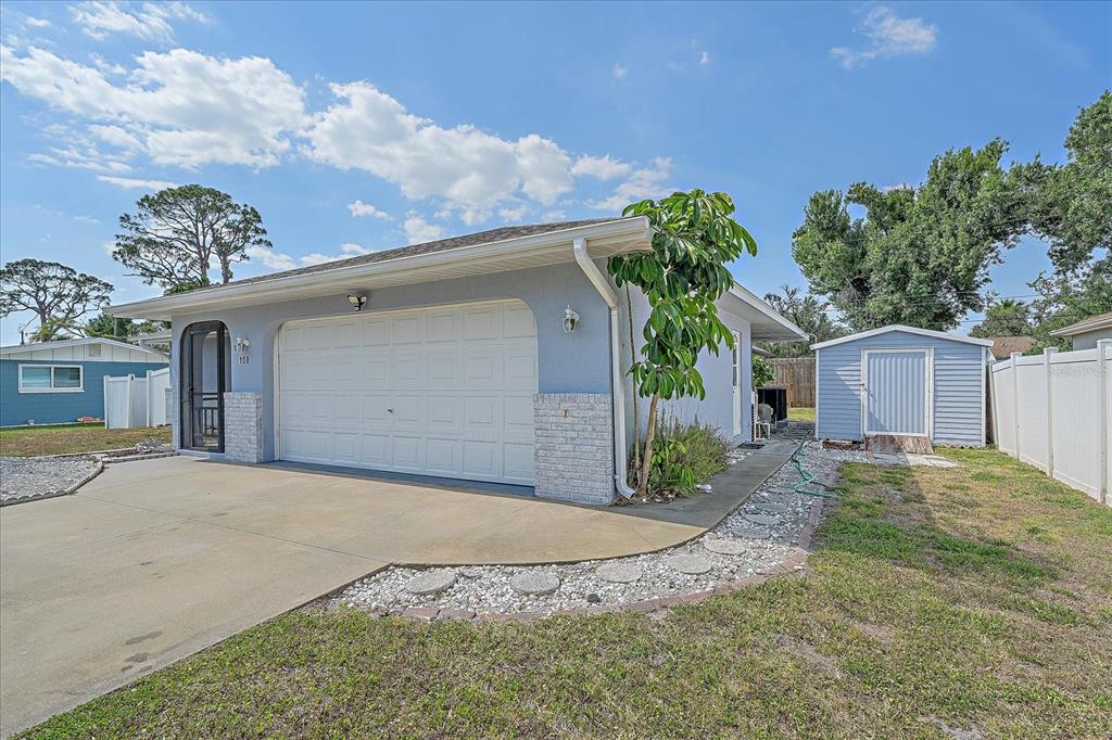 A light blue house with a two-car garage, a side shed, and a concrete driveway — 108 STANFORD ROAD, VENICE, FL