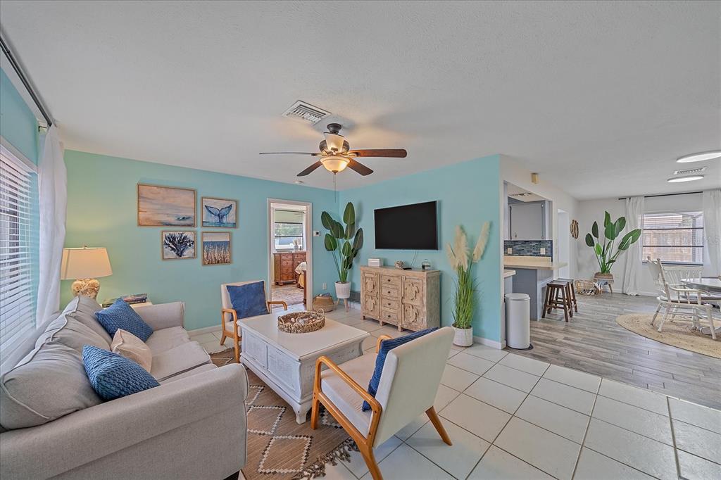 A living room with light blue walls, tile flooring, a sofa, and a dining area — 108 STANFORD ROAD, VENICE, FL