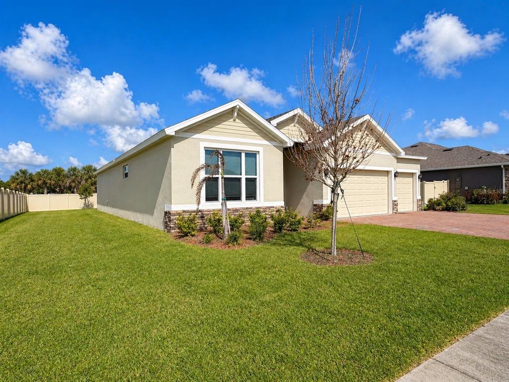 A single-story house with a beige stucco exterior, stone accents, and a two-car garage — 6860 CAMEO DR, GRANT VALKARIA, FL